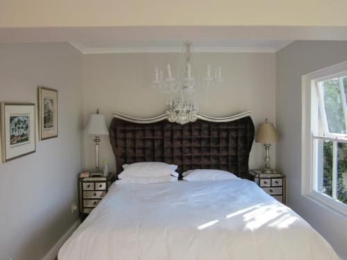 a bedroom with a large white bed with a chandelier at The Gregoire Boutique Villa in Hermanus