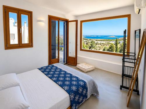 a bedroom with a bed and a large window at villa kite paros in Pounda