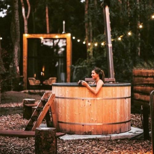 a woman sitting in a wooden tub in a playground at Tiny House of Happiness - shared hot tub in Otterlo