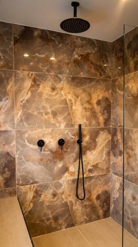 a bathroom with a shower with a stone wall at תחנת גן עדן - Paradise Station in Menaẖemya