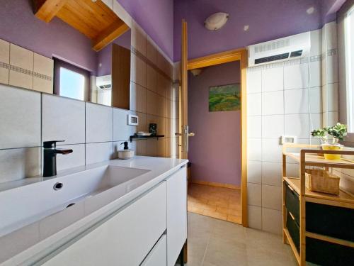 a kitchen with a white sink and purple walls at Apartment Rosa Istria in Buje
