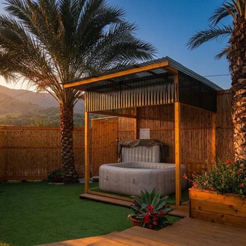 a bed in a gazebo in a yard with palm trees at תחנת גן עדן - Paradise Station in Menaẖemya