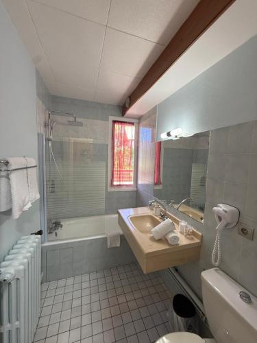 a bathroom with a sink and a tub and a toilet at Hôtel Restaurant La Pendine in Puy-Saint-Vincent