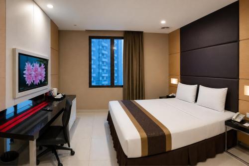 a bedroom with a bed and a desk and a television at B Fashion Hotel in Jakarta