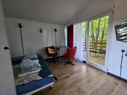 a bedroom with a bed and a table and a balcony at Siedlisko Bartek domki na Kaszubach nad jeziorem Mausz in Sulęczyno