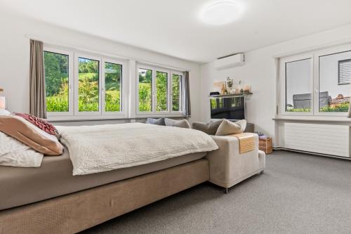 a bedroom with a bed and a couch and windows at peaceful tiny house near forest in Rorschacherberg