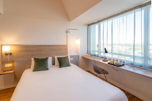 a bedroom with a large white bed and a window at Sure Hotel by Best Western Dijon Sud in Chenôve