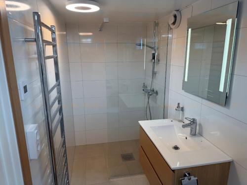 a bathroom with a sink and a shower with a mirror at Lägenhet 36B in Båstad