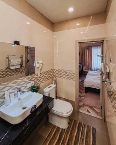 a bathroom with a sink and a toilet and a bedroom at Guest house TWINS in Tashkent
