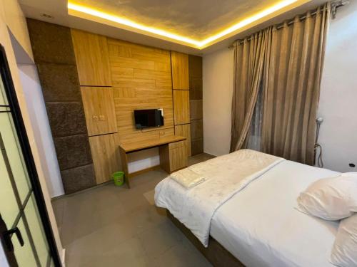 a bedroom with a bed and a tv on a wall at MOTISOFT Hotel in Yenagoa