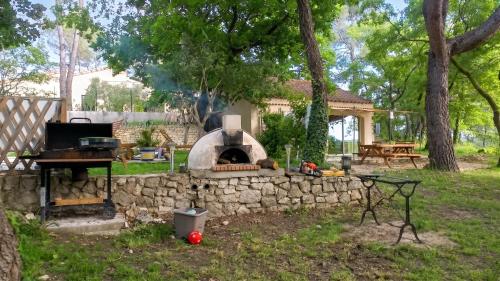 a stone wall with a pizza oven in a yard at Maison confortable à Velleron de 50 m² avec piscine in Velleron