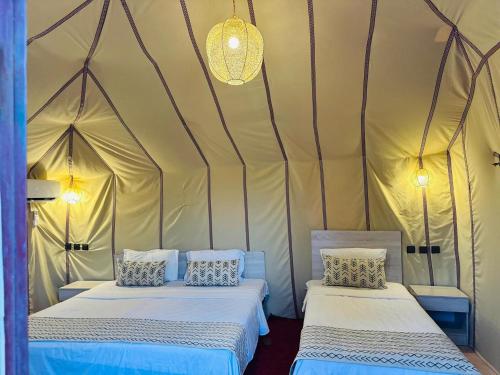 a room with two beds in a tent at Camels house apartment in Adrouine