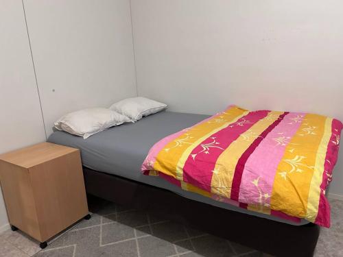 a bed with a colorful blanket and a wooden cabinet at Private Room in Shared Apartment in Vaasa