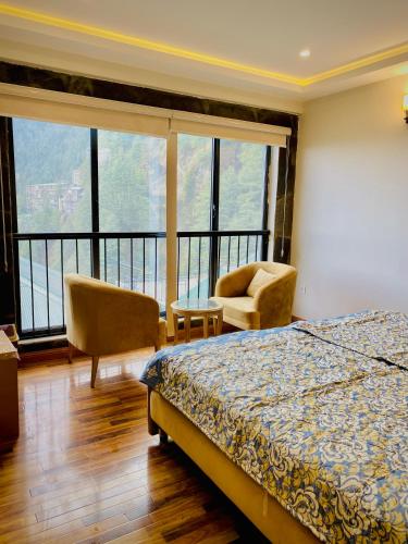 a bedroom with a bed and chairs and windows at Snowra heights in Abbottabad