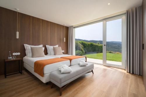 a bedroom with a large bed and a large window at Agua Hotels Mondim de Basto in Mondim de Basto