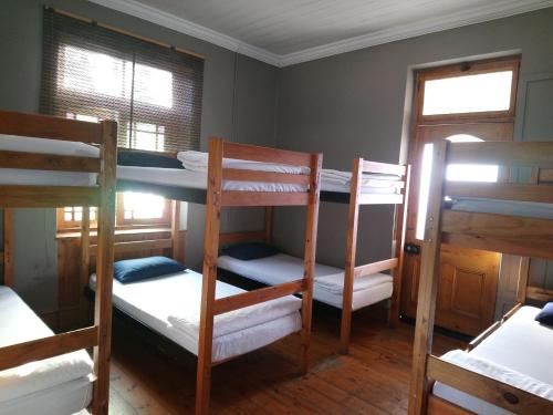 a room with three bunk beds and two windows at Hostel Villa Nova in Mossel Bay