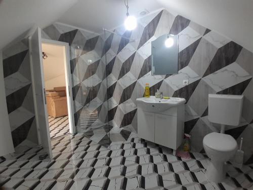 a bathroom with a black and white tiled wall at Apartman Maga 2 in Gnjilišta