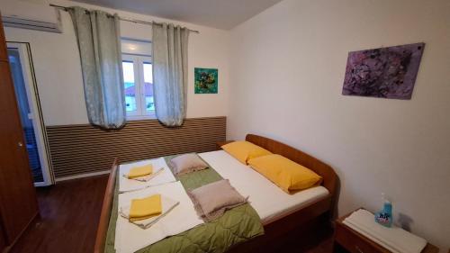 a bedroom with a bed with yellow pillows and a window at Apartments Vukelić in Starigrad
