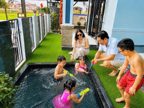 a family playing in the water in a pool at Homestay ĐAN MY 2 in Trung Nghĩa