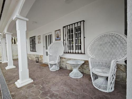 a group of white wicker chairs and tables in a room at Chalet cerca de la playa de Esmelle in Pedreira