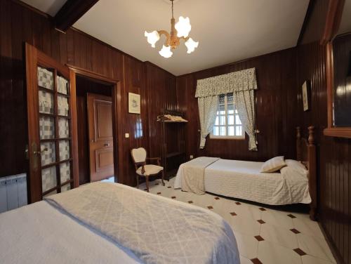 a bedroom with two beds and a chandelier at Chalet cerca de la playa de Esmelle in Pedreira