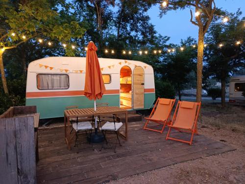 a rv with a table and chairs and an umbrella at Camping Arribes del Duero in Lumbrales