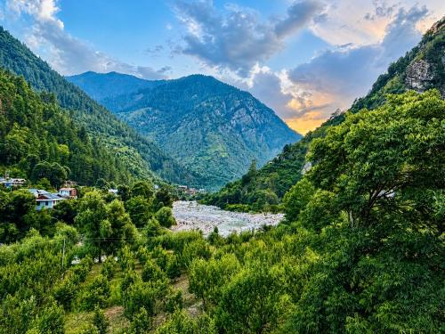 a valley in the mountains with a river and trees at Tirthan Wood , a river view cottage in Banjār