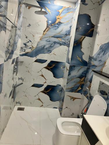 a bathroom with a toilet and a marble wall at Landmark Hotel & Resort in Taiwāl