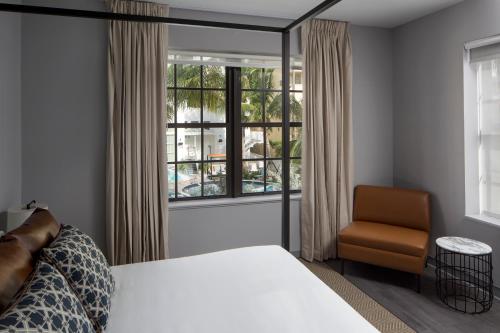 a bedroom with a bed and a chair and a window at Hotel Rendale Miami Beach in Miami Beach