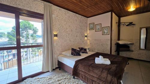 a bedroom with a bed and a large window at Residencial Borges Canela in Canela