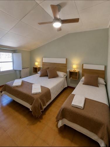 a bedroom with two beds and a ceiling fan at Ca Muns Pares in Ginestar
