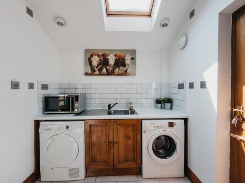 a kitchen with a sink and a washer and dryer at Peak Cottage in Matlock