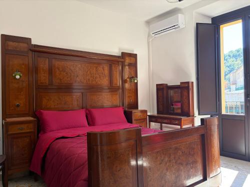 a bedroom with a large wooden bed with red sheets at Casa Caterina in Graniti