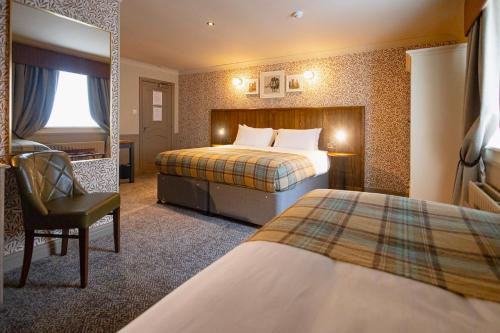 a hotel room with two beds and a chair at The Red Lion Hawkshaw in Bury