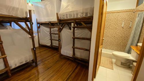 a room with three bunk beds and a toilet at HIDDEN HOSTAL MONTANITa in Montañita