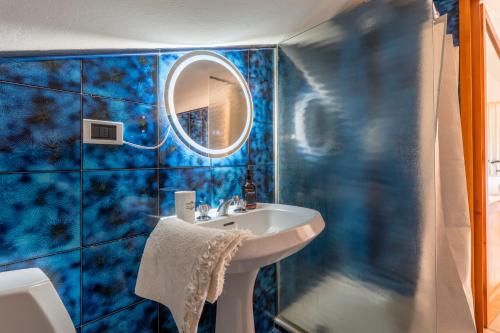 a blue tiled bathroom with a sink and a mirror at Maison Blanche in Bordighera