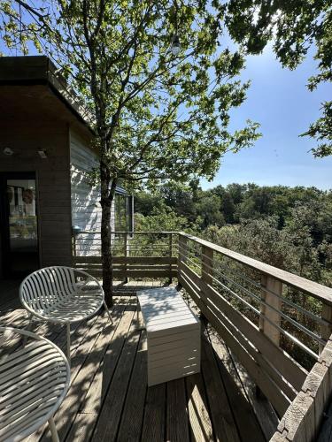 a deck with two chairs and a table and a tree at Carrière Sauvage in Pont-Aven