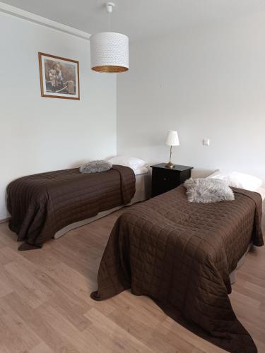 a bedroom with two beds and a lamp on a wooden floor at Walhalla Kuhala apartment in Forssa