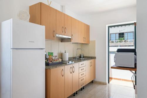 a kitchen with wooden cabinets and a white refrigerator at Apartamentos Bellavista in Puerto del Carmen