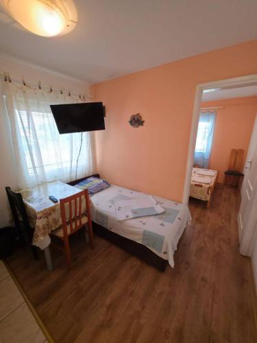 a bedroom with a bed and a table and a television at Deskom Zelena Vila in Veliko Gradište