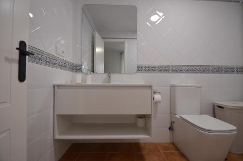 a white bathroom with a toilet and a mirror at Playa Grande SOLMARES in Isla del Moral