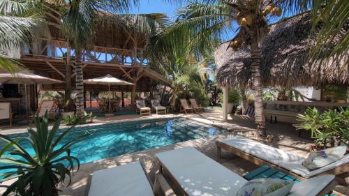 a swimming pool with palm trees and a resort at Nuevo NAYAL in Las Peñitas