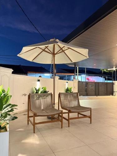 two chairs and an umbrella on a patio at Chin Villa in Simpang Ampat