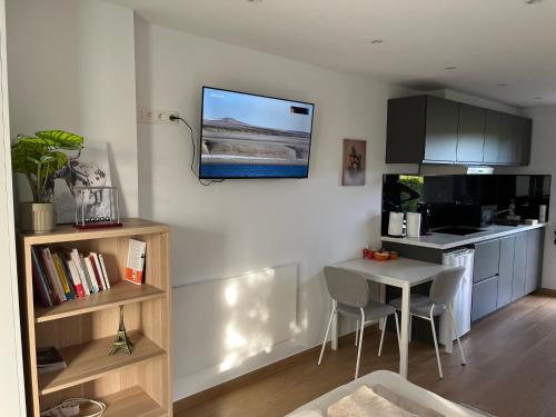 a kitchen with a table and a tv on the wall at Aux Boutons d'Or in Namur