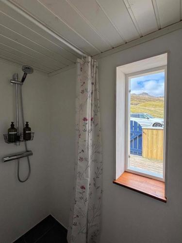 a room with a window and a shower curtain at Cabin by Gáansá in Sandavágur