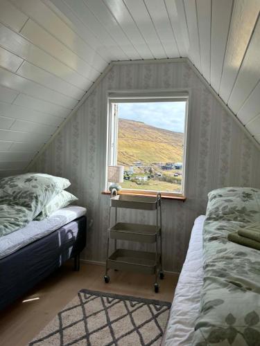 a small room with two beds and a window at Cabin by Gáansá in Sandavágur