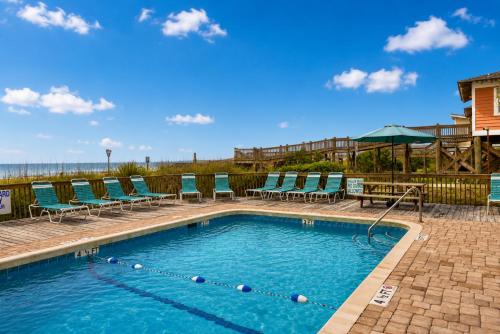 a swimming pool with chairs and a table at Ocean Forest Colony in Myrtle Beach