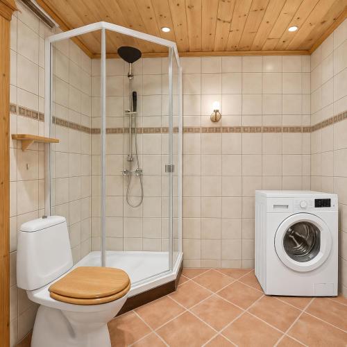 a bathroom with a shower toilet and a washing machine at Hus med panoramutsikt i Bud in Bud