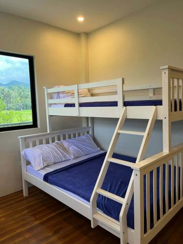 a bedroom with two bunk beds and a window at Casa de Lilong in Mahinog