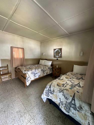 a bedroom with two beds and a chair at room #2 Rancho Meling in Camalú
